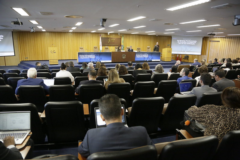 Foto do auditório com juízes e juízas na plateia e dois palestrantes na mesa.